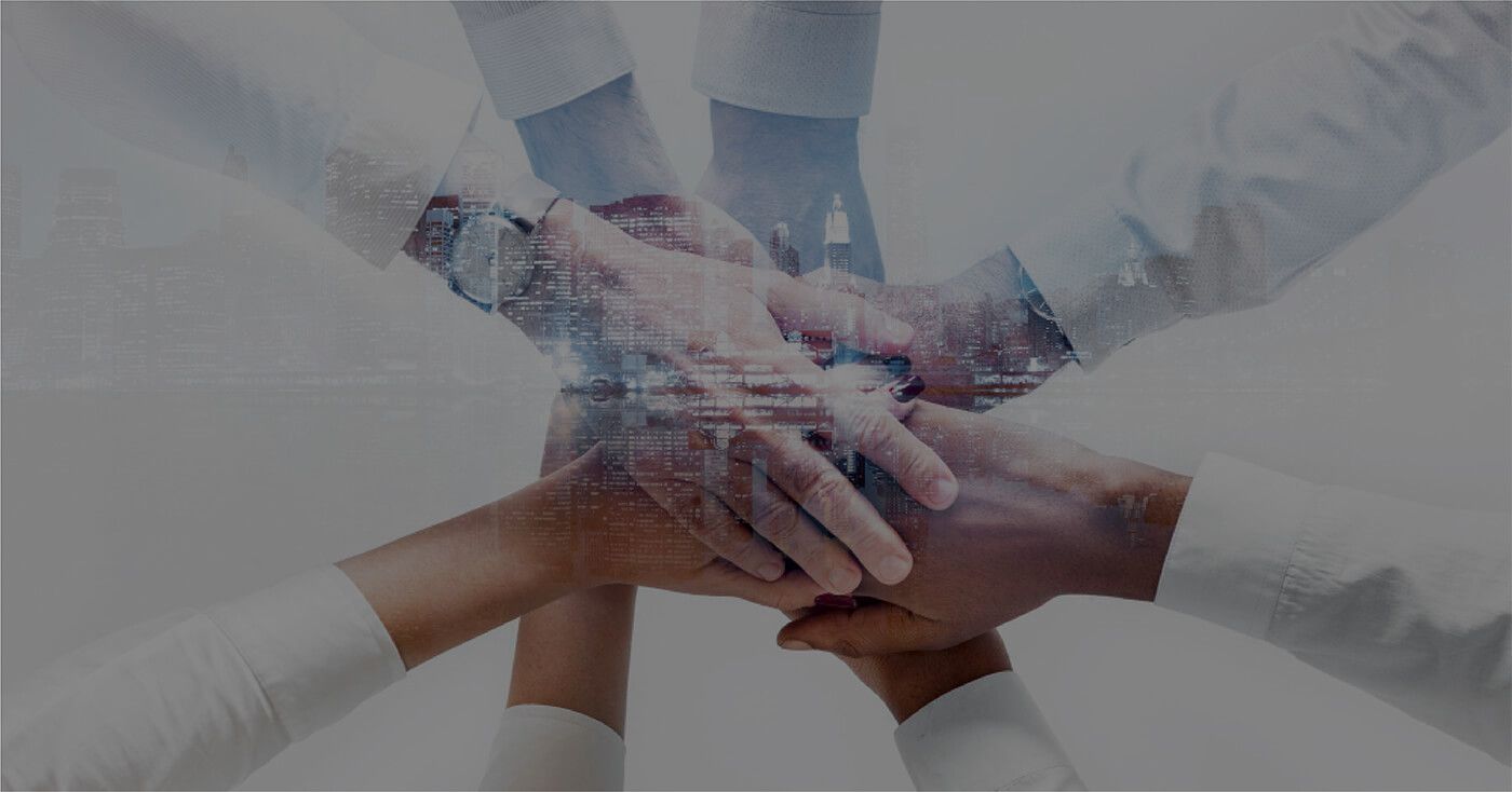 Hands stacked together, overlayed with cityscape, symbolizing teamwork.