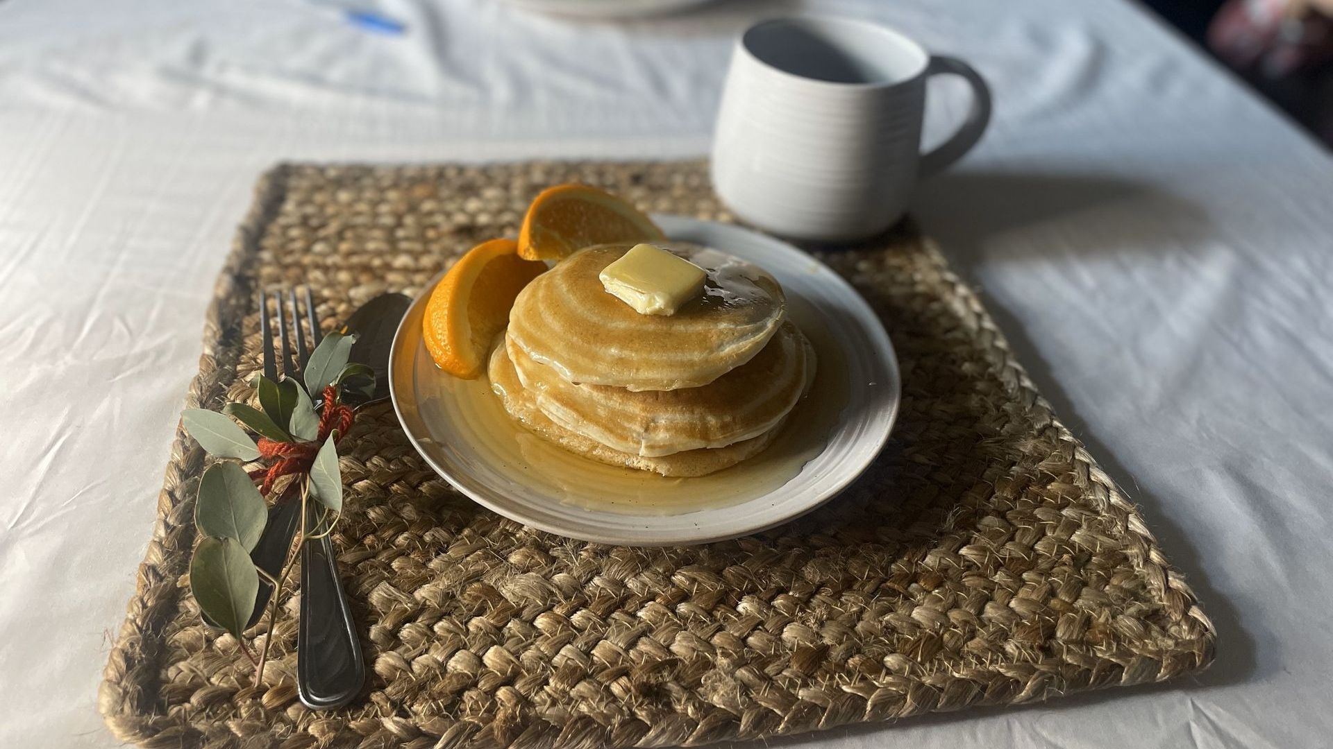 photo of a stack of pancakes and cup of coffee on a placemat