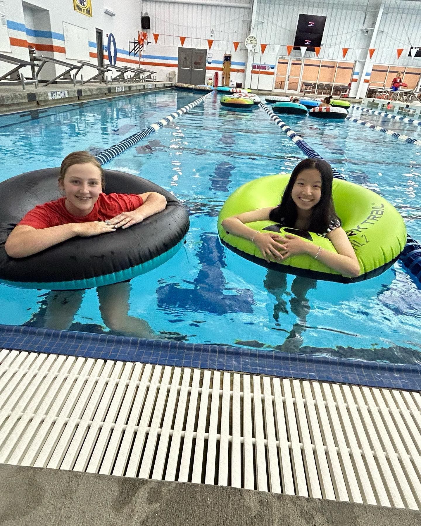 Two kids floating in inner tubes in a pool.