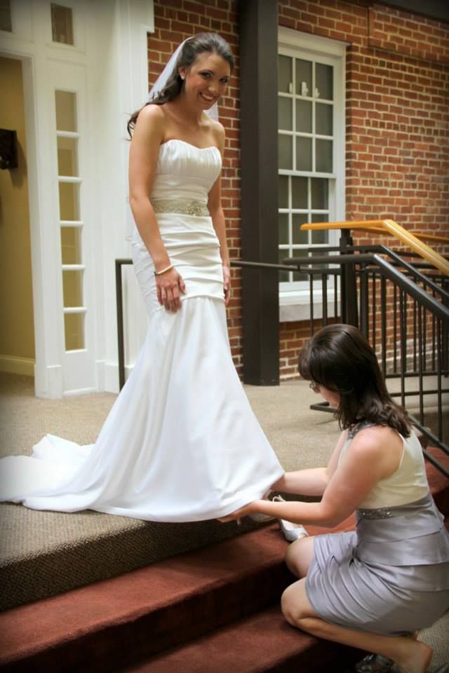 Lynn adjusting Amanda's wedding dress in the Sharp atrium on Union's campus.