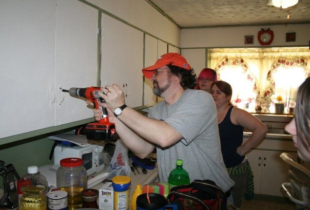 Miller using an electric drill with a group of students in a home during Repair Affair.