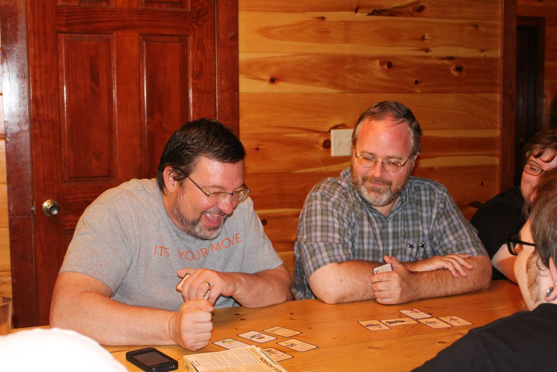Miller laughing while sitting next to Bruce Cory and playing a board game with students.