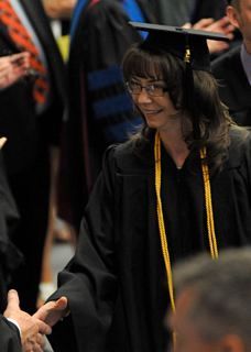 Lynn in her graduation cap and gown shaking someone's hand.
