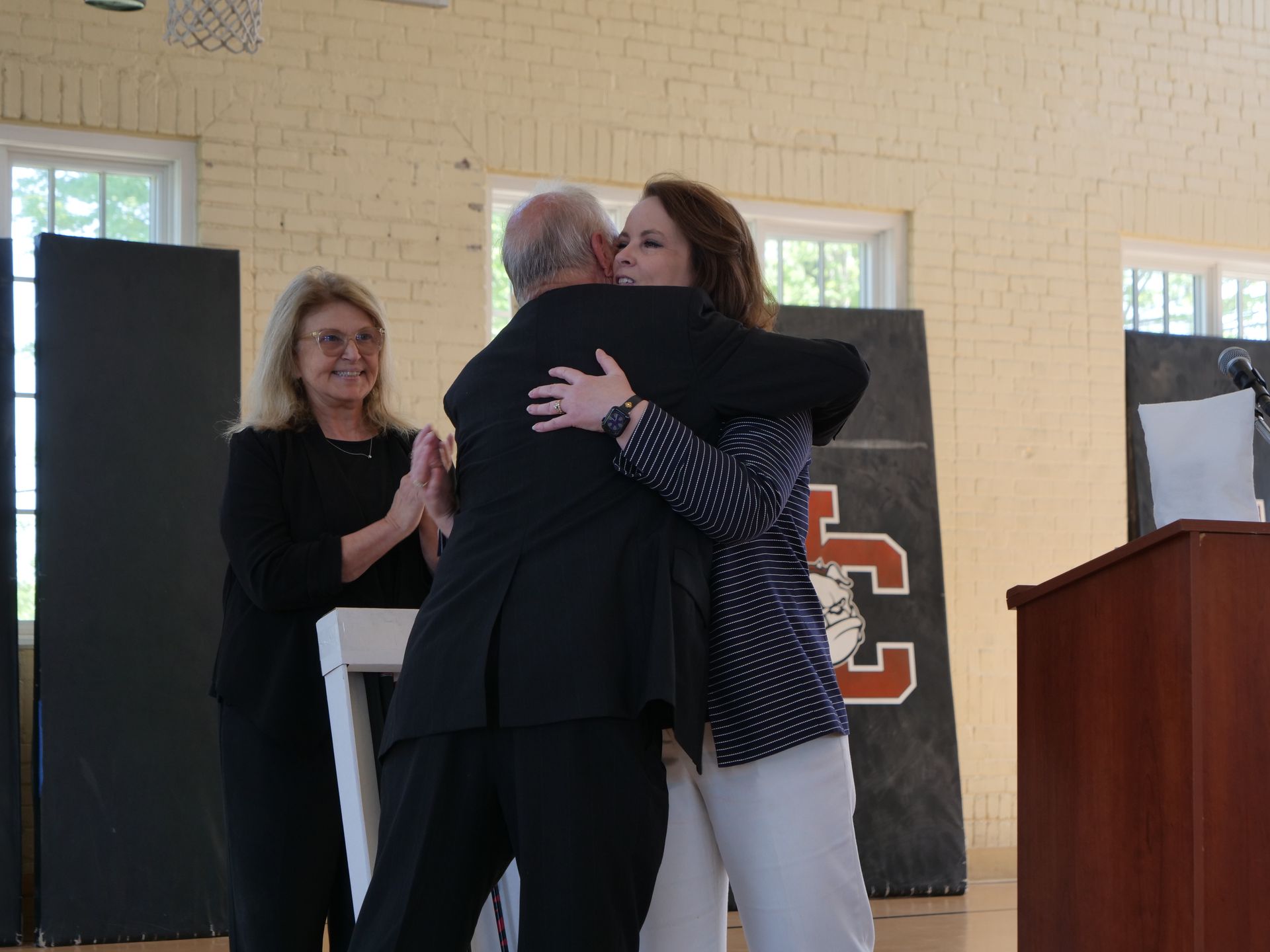 Dr. Inkster hugs Dr. Greer while Dr. Hawkins looks on.