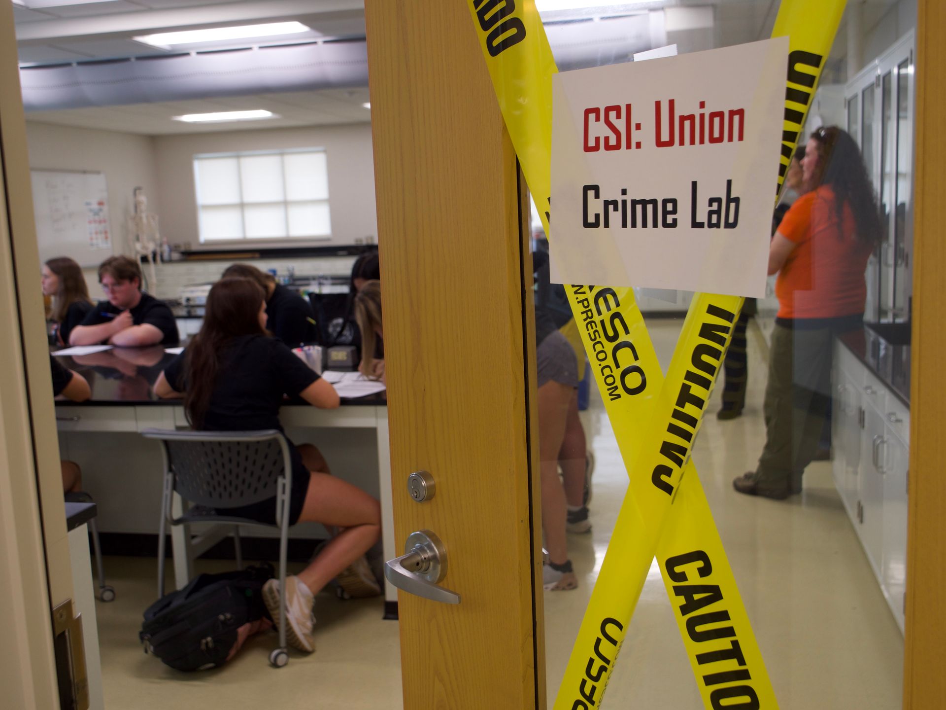A door opening to the Union Crime Lab with students sitting at a table.