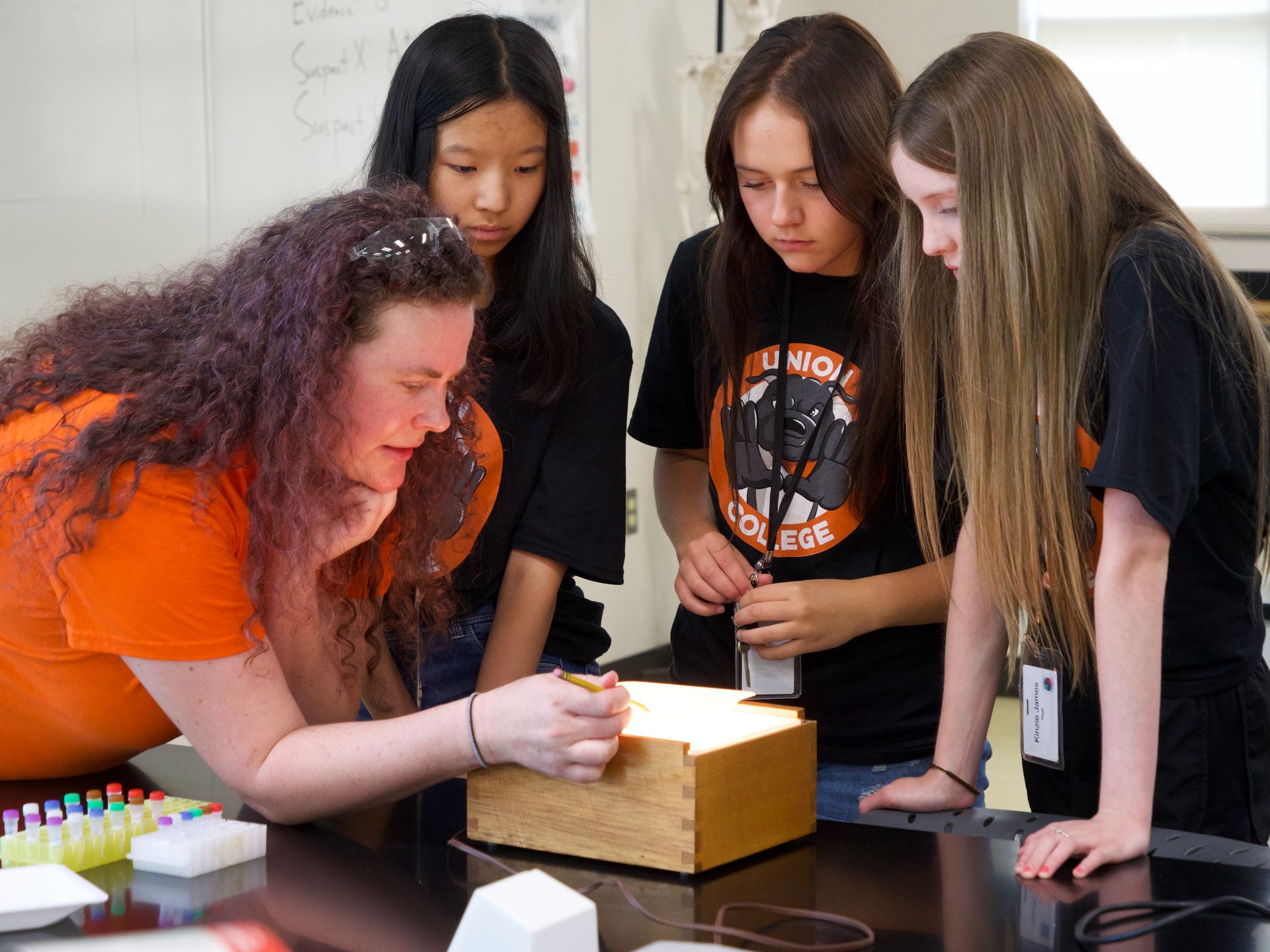 Students examining a sample over a light box with the assistance of professor Libby Megna.