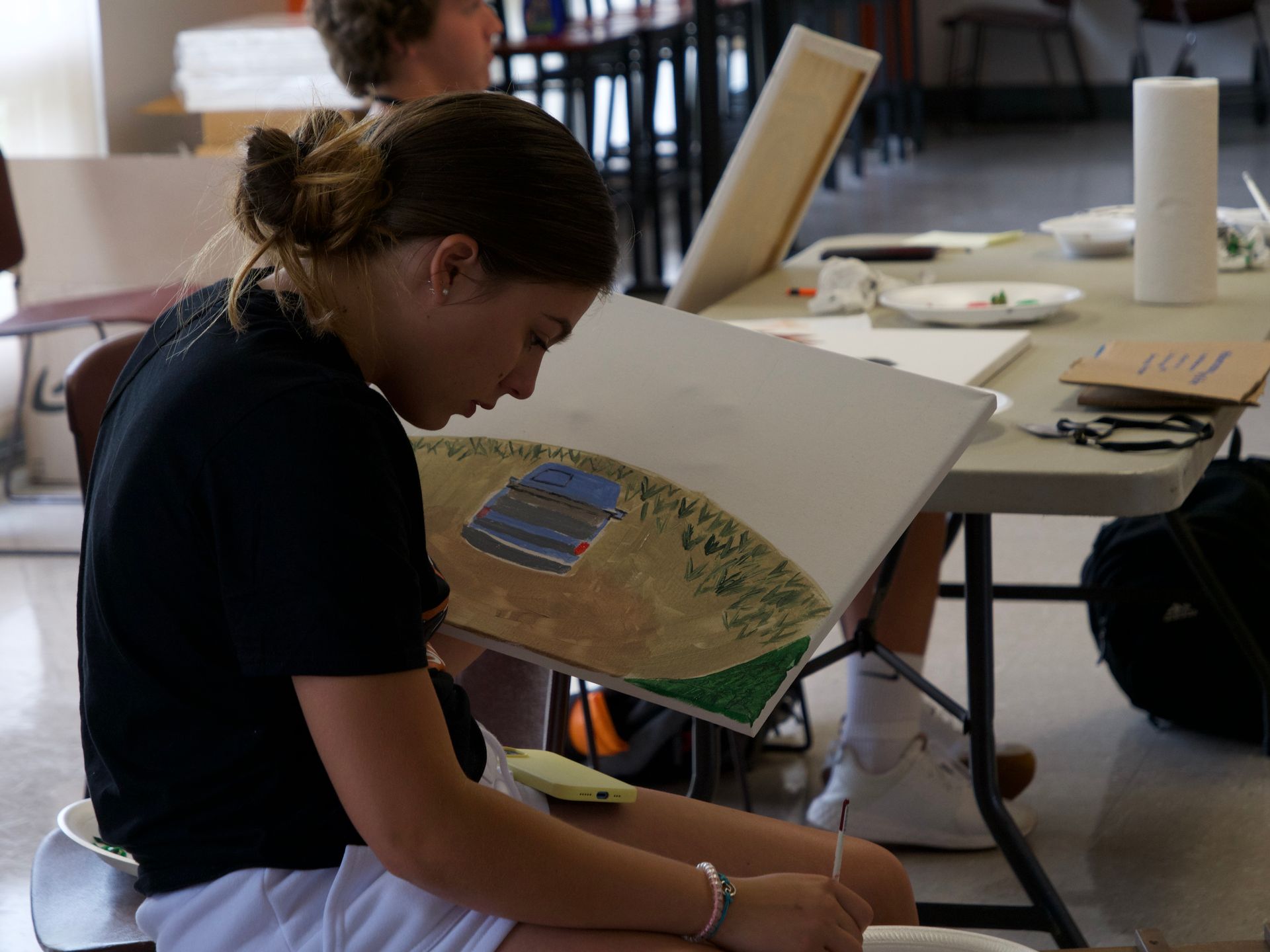 A student painting a canvas as part of an art activity.