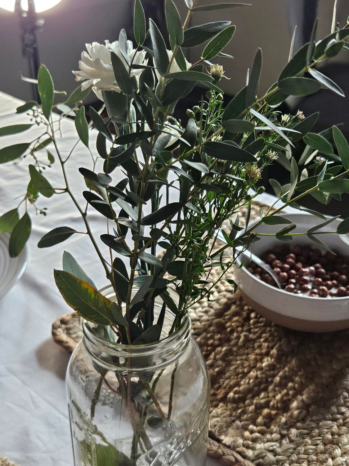 A bowl of cereal on a woven tray sits beside decorative green plants.