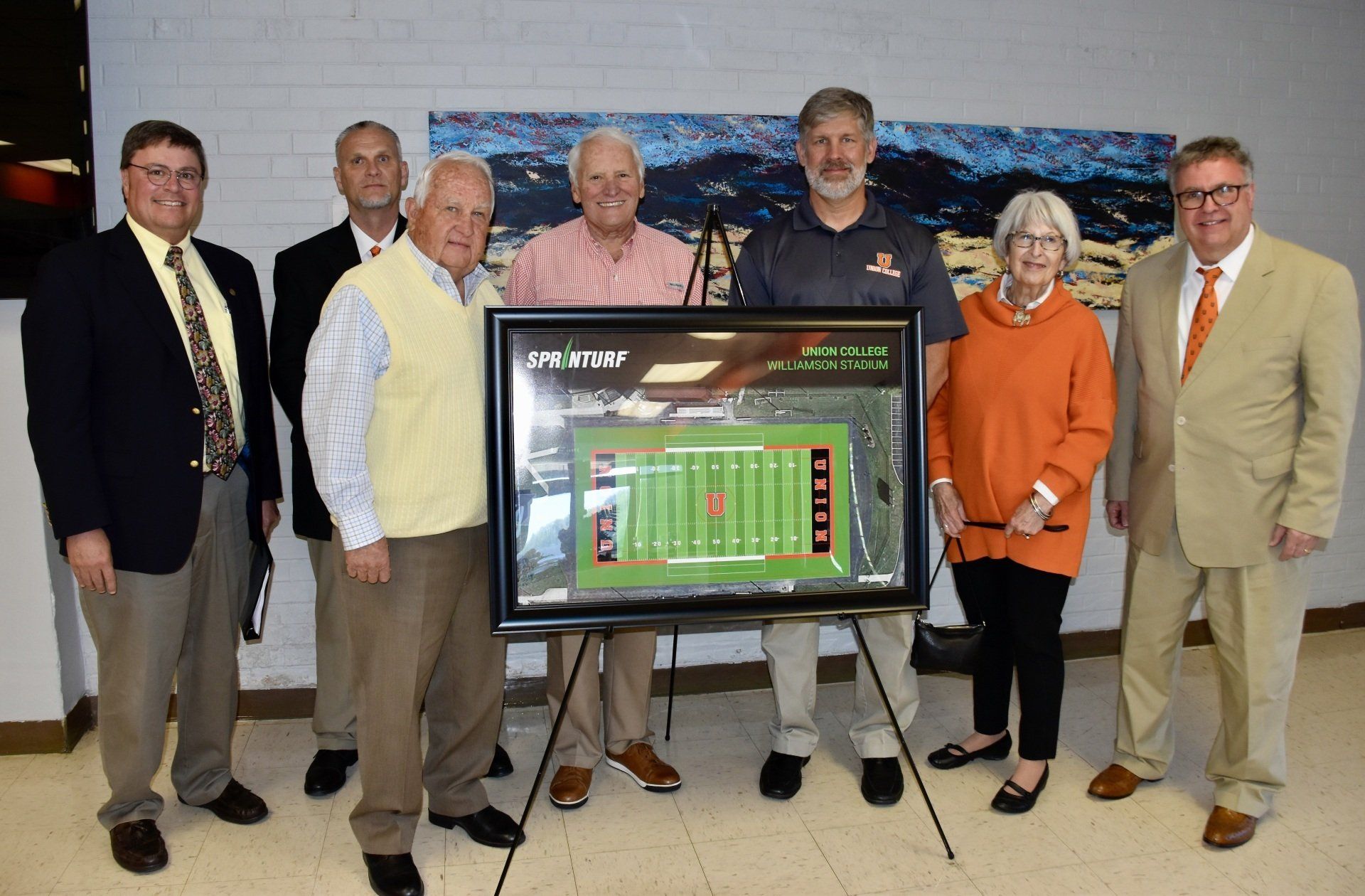 Members of the Athletic Committee stand behind rendering of new field.