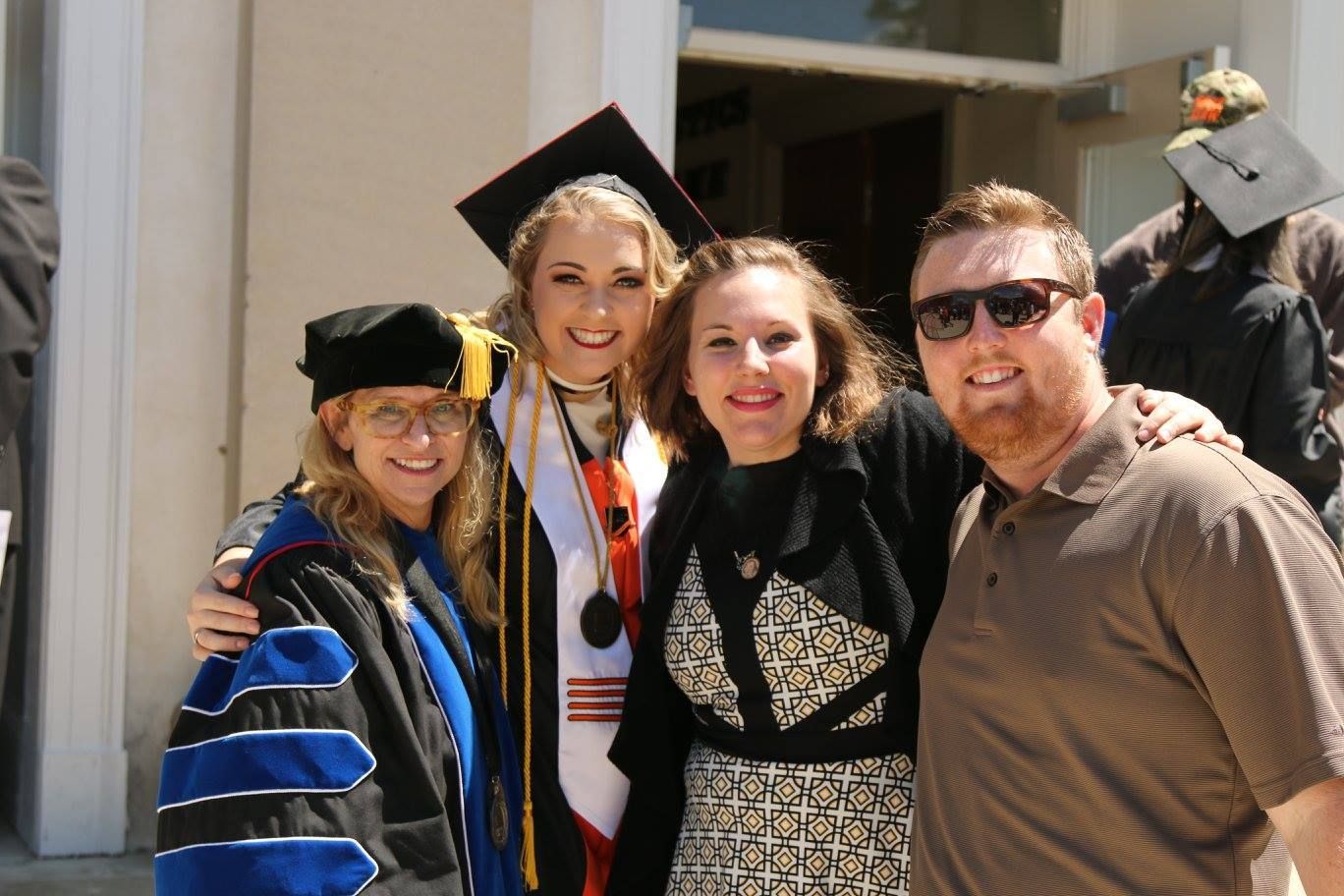 Dr. Christine Marley-Frederick standing with a graduating student and her family or friends at commencement.
