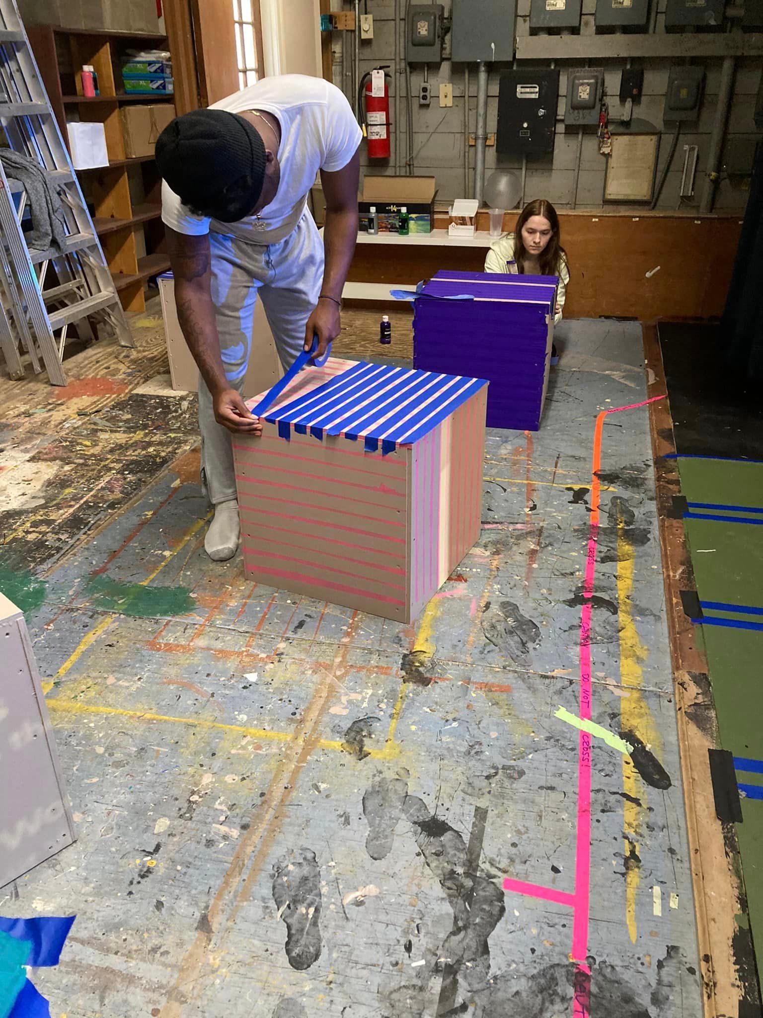 Students designing pink and purple boxes to be used for the set.