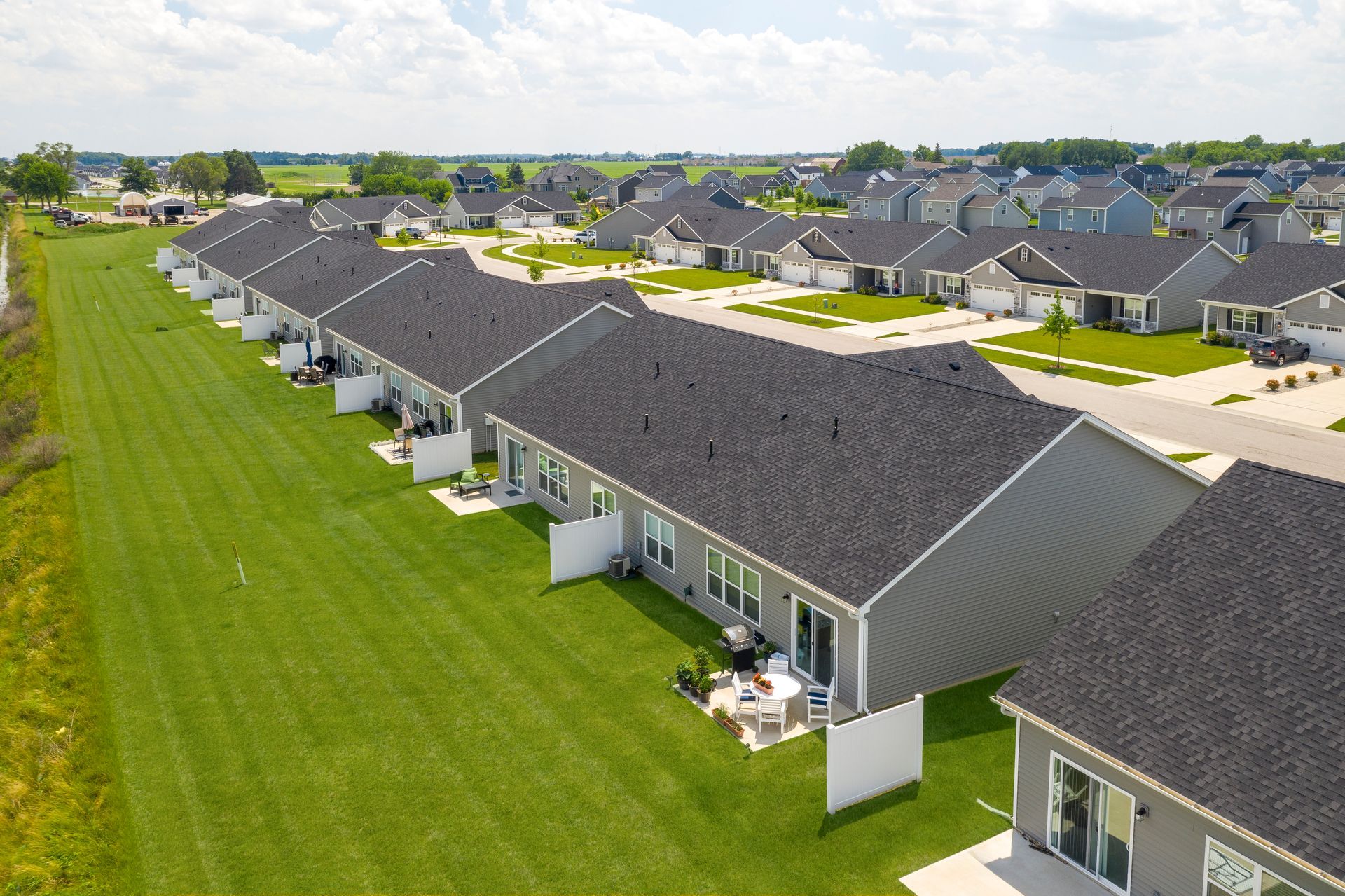 Row of modern gray houses with black roofs and green lawns.