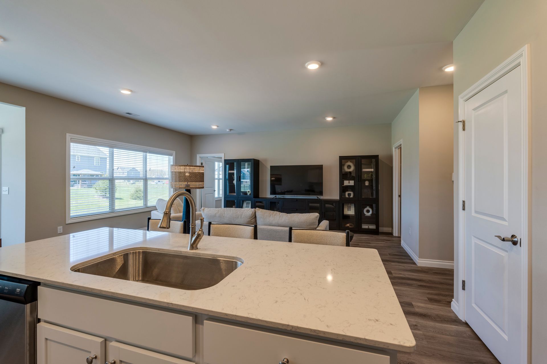 Kitchen island with sink, facing open living room with a sofa, TV, and large windows.