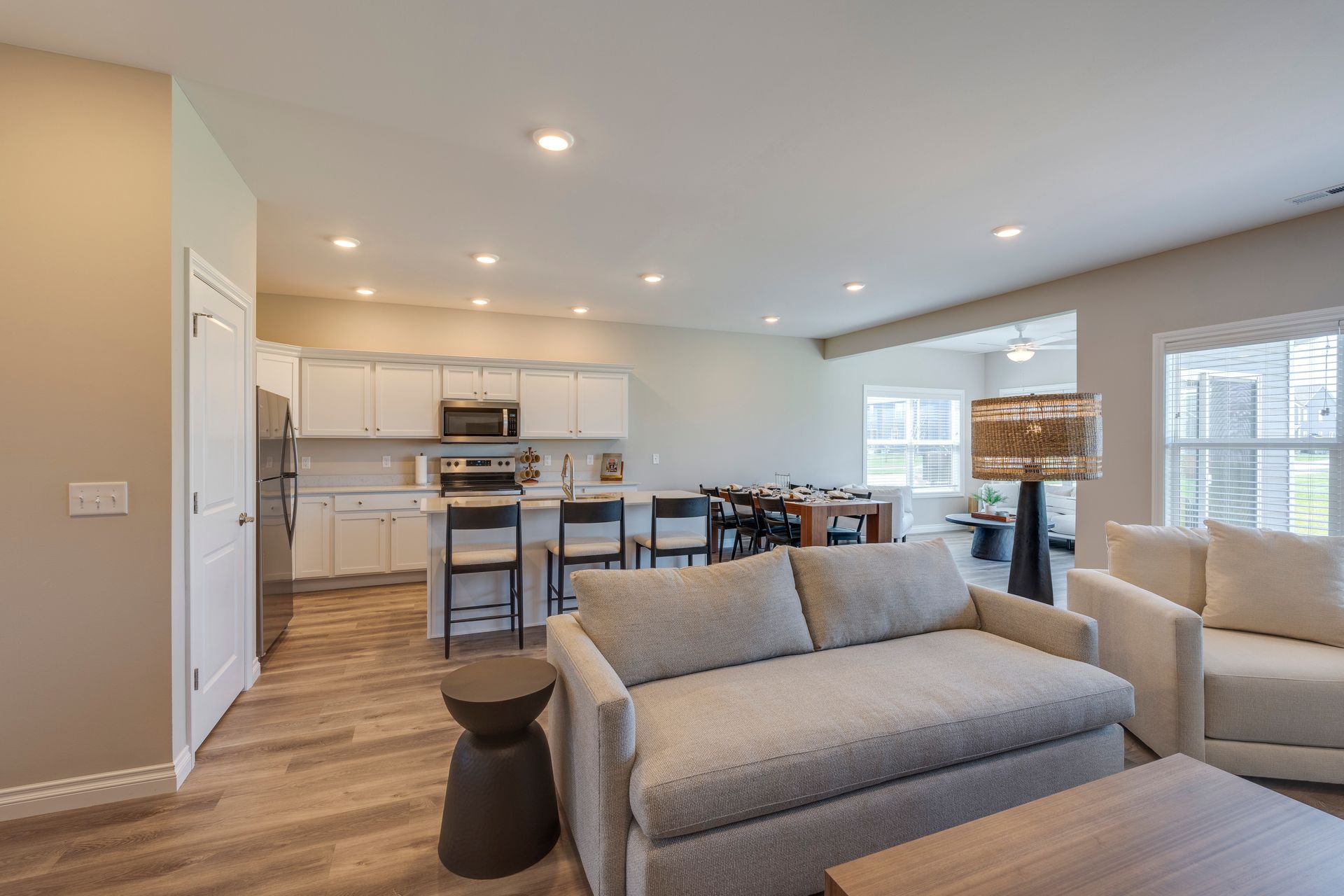 Open-concept living space with kitchen, dining area, and living room furnished in neutral tones.