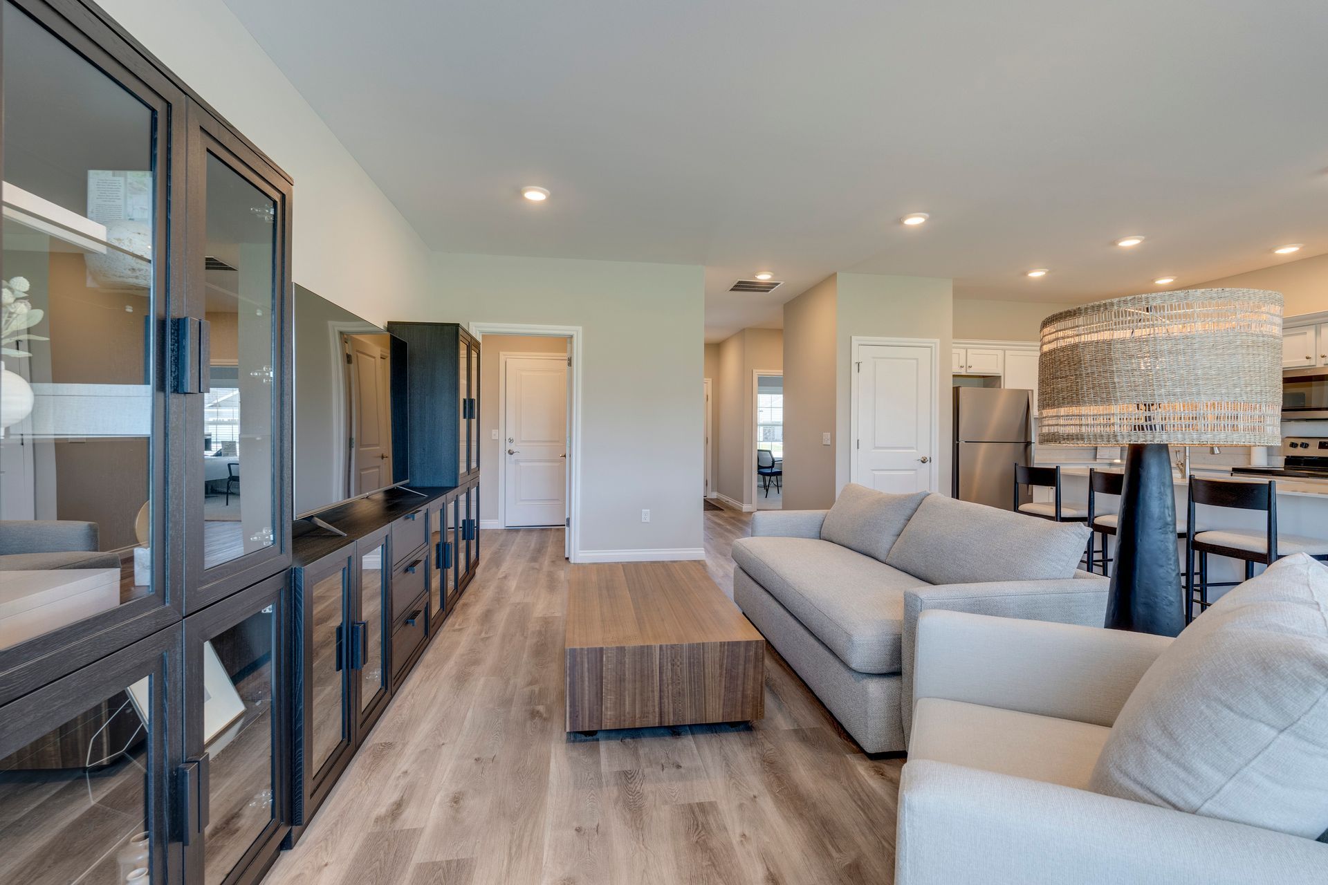 Spacious living room with light wood floors, gray sofa, coffee table, and dark cabinet against the wall.
