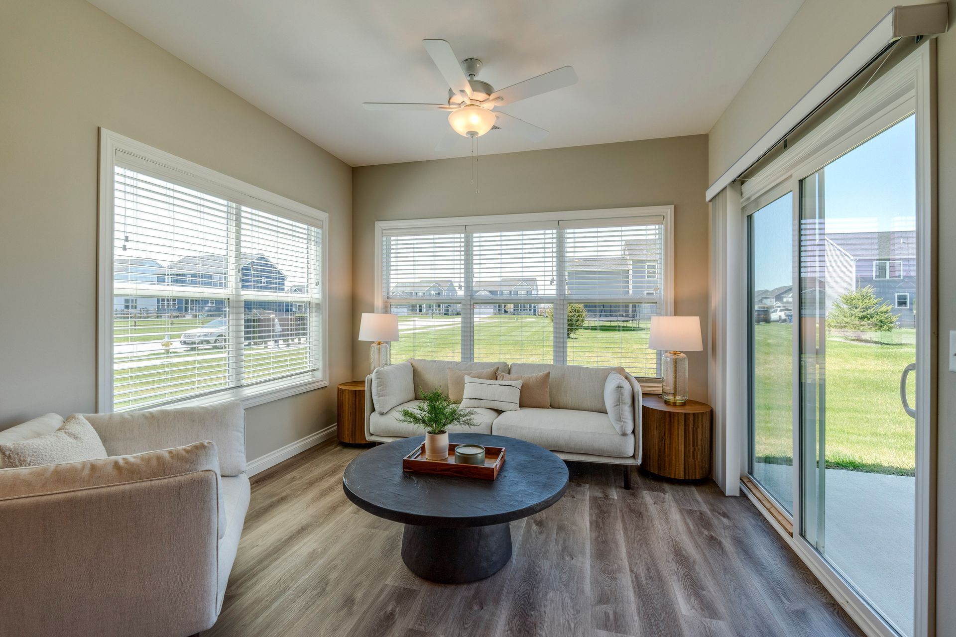 Living room with a sofa, chairs, a coffee table, and large windows overlooking a lawn.