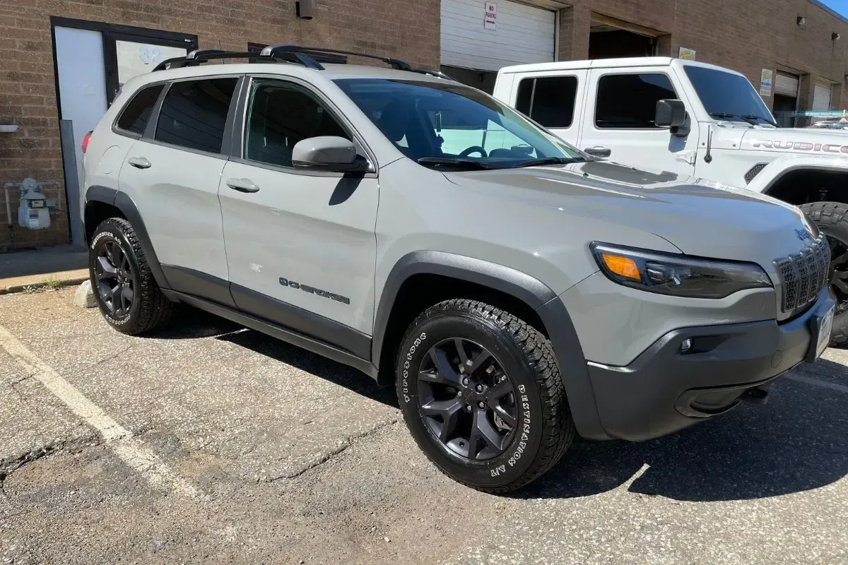 Gray Jeep Cherokee SUV with black accents parked next to a white Jeep.