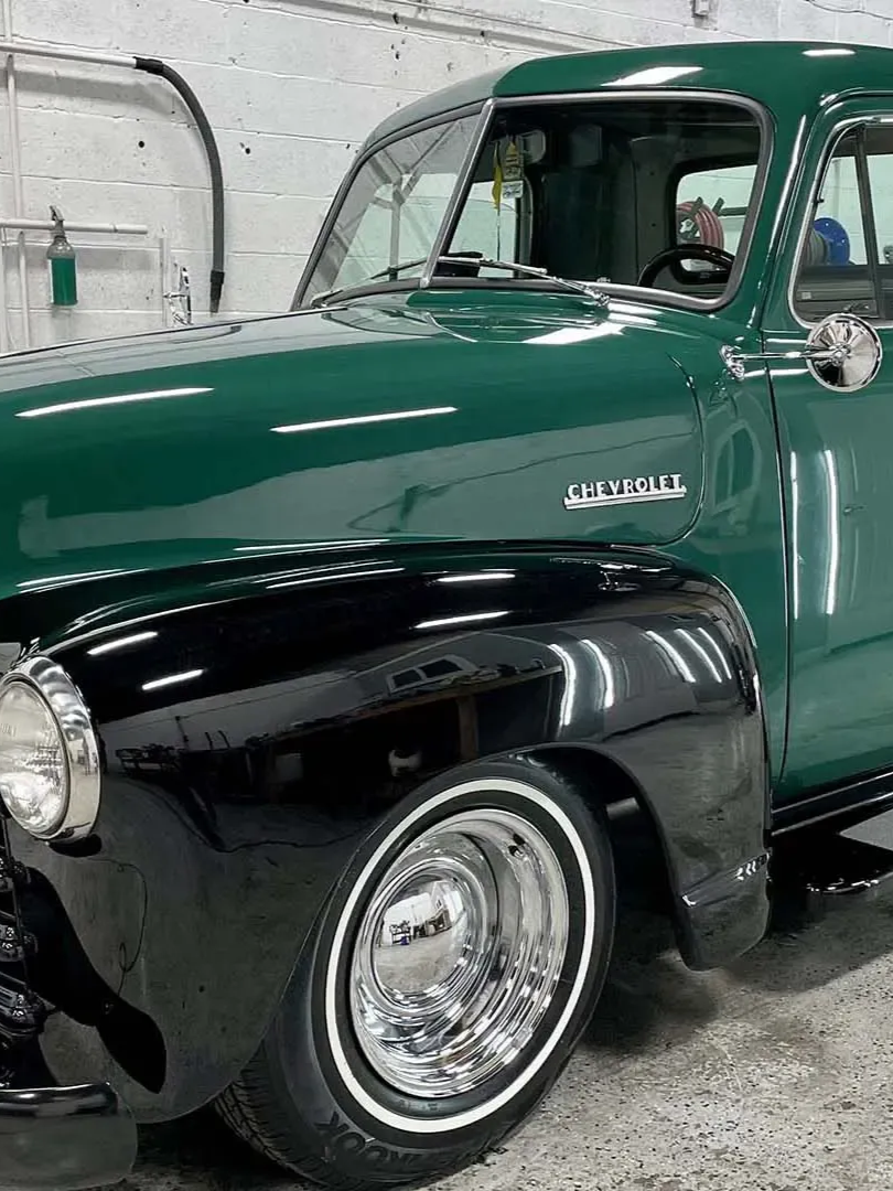 Green and black vintage Chevrolet pickup truck with whitewall tires.