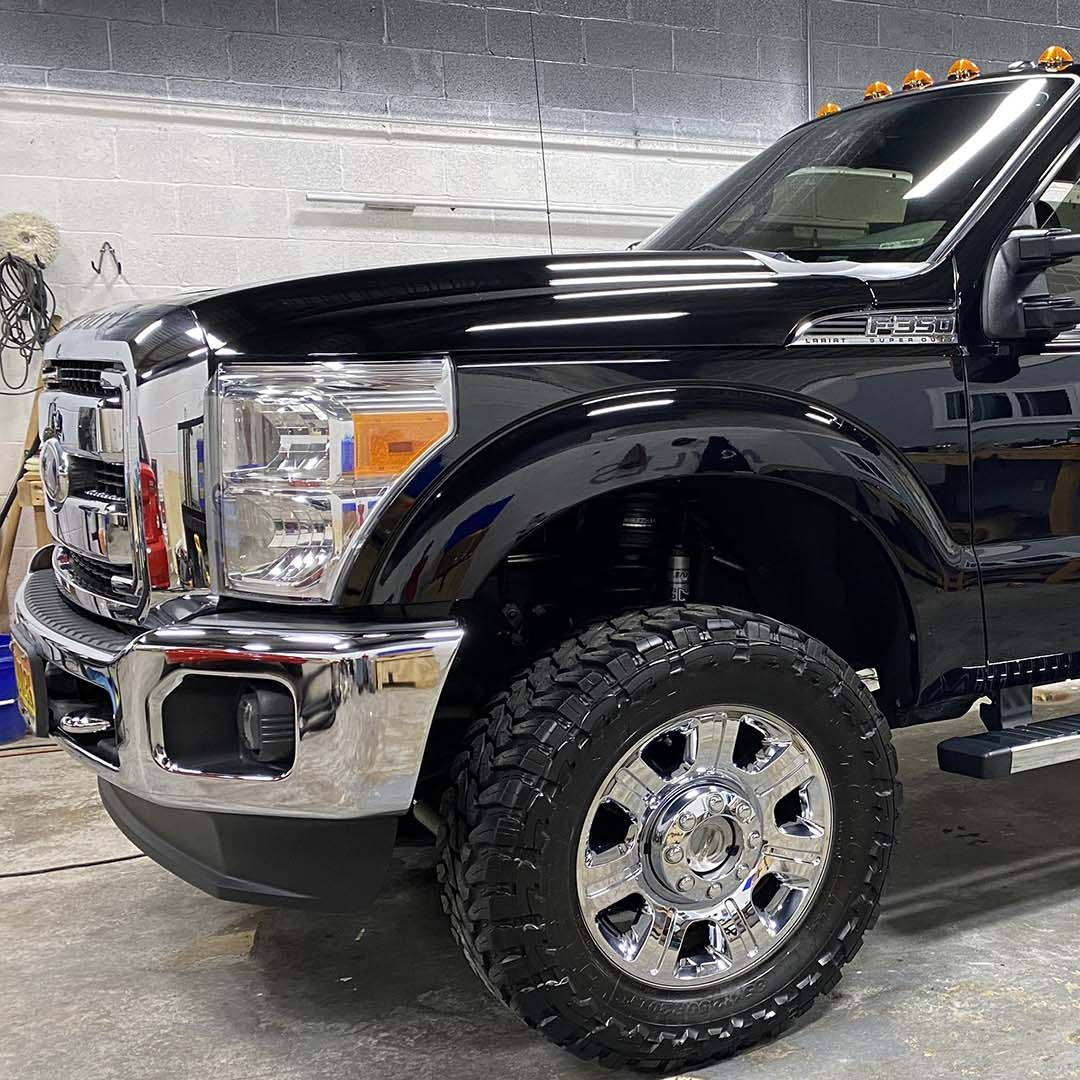Black pickup truck with chrome accents and large off-road tires.