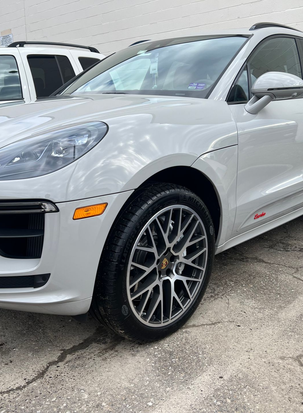 Silver Porsche Macan GTS with black wheels parked on a cracked concrete surface.