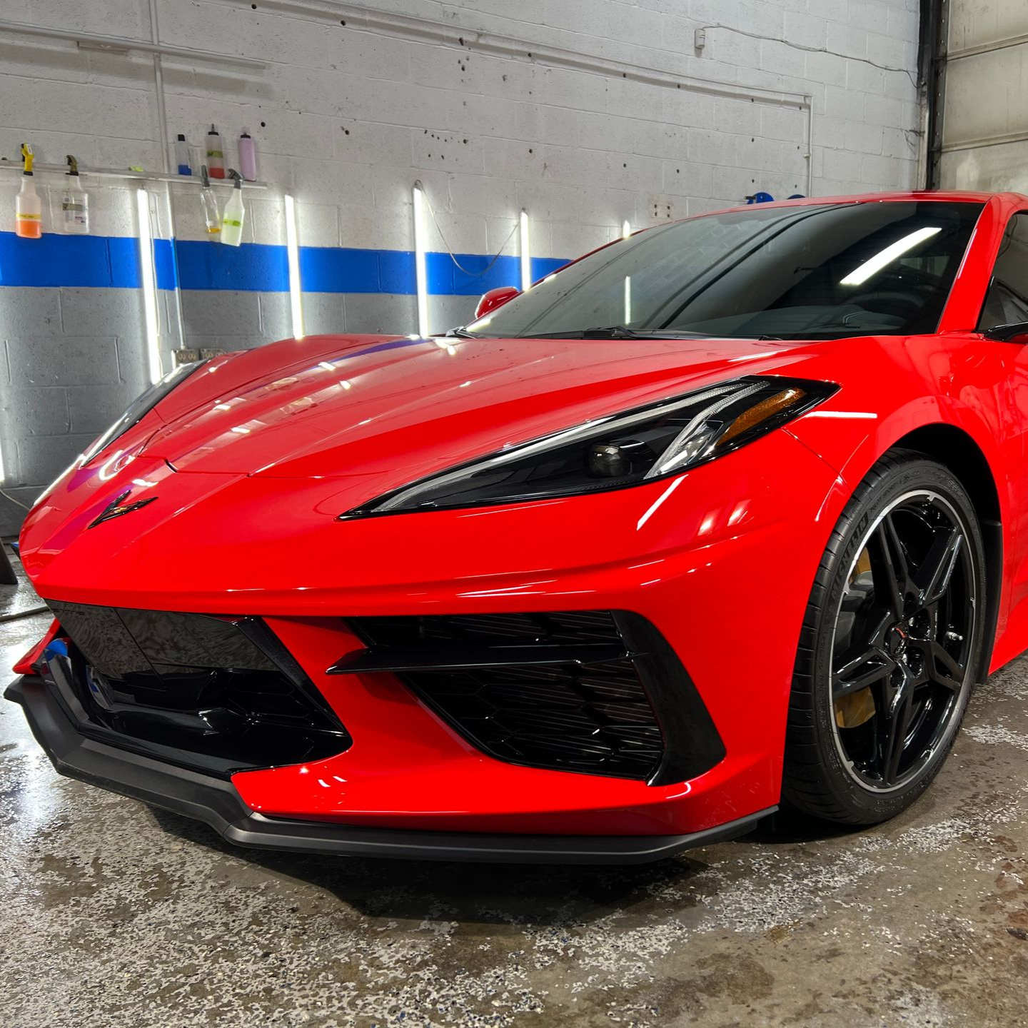 Red sports car in a garage. It is new and clean with black wheels.