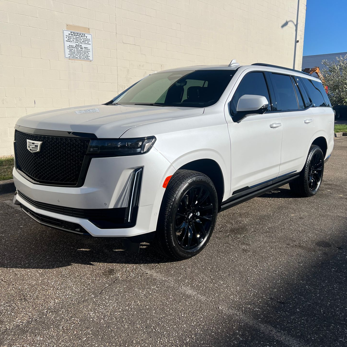 White Cadillac Escalade SUV with black wheels parked on asphalt.