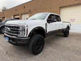 White and brown Ford truck parked outside a building with black wheels and tires.