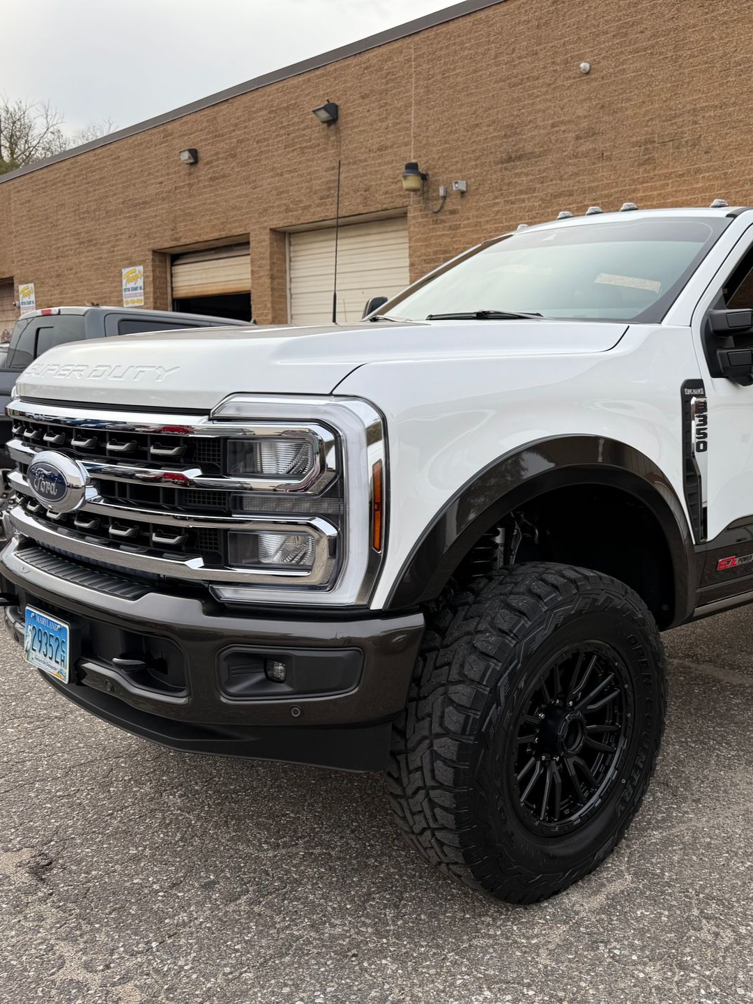White Ford truck with brown accents parked outside a building.