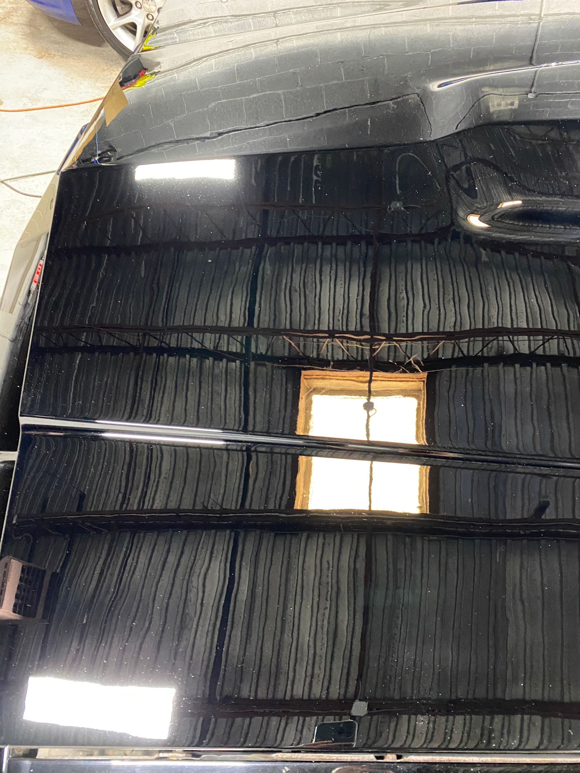 Black car roof with reflections, light illuminating the surface.