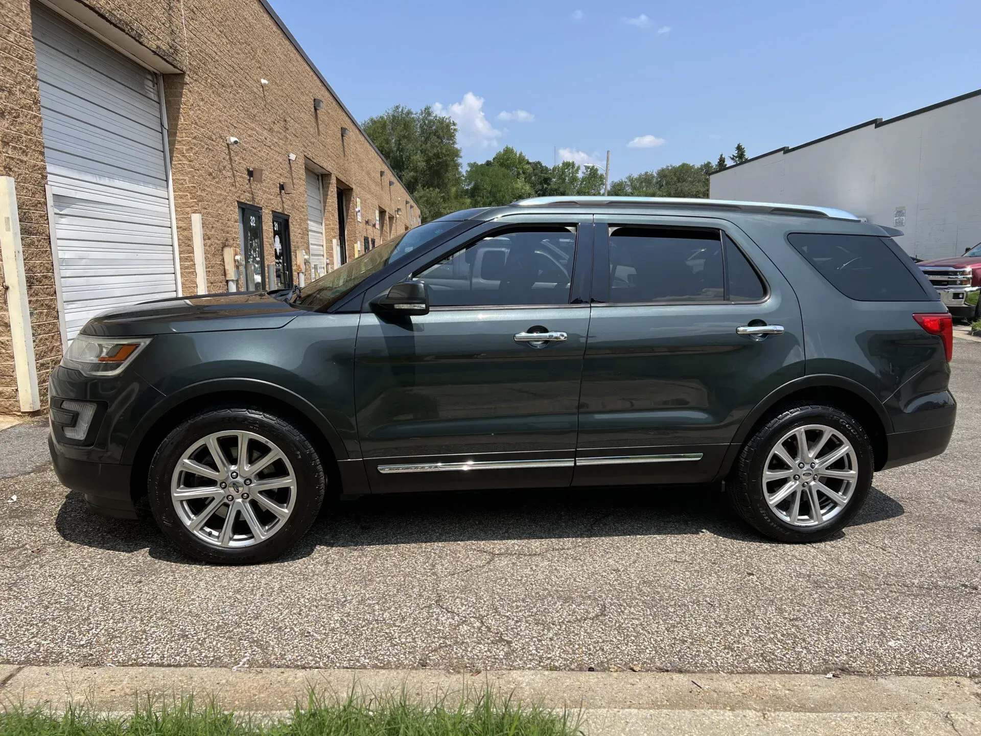 Green Ford Explorer parked in front of a brick building on a sunny day.