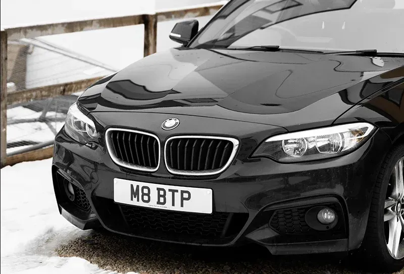 Black BMW car with a front view. License plate reads