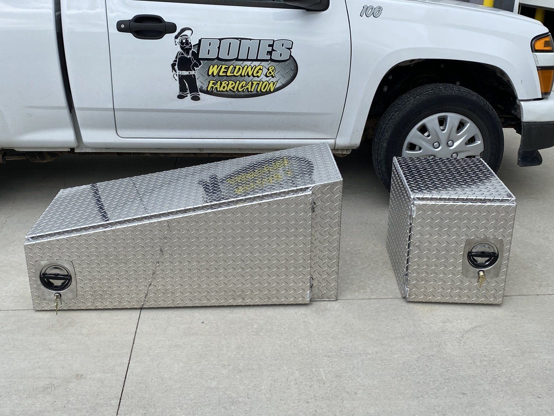 A white truck with two aluminum boxes in front of it