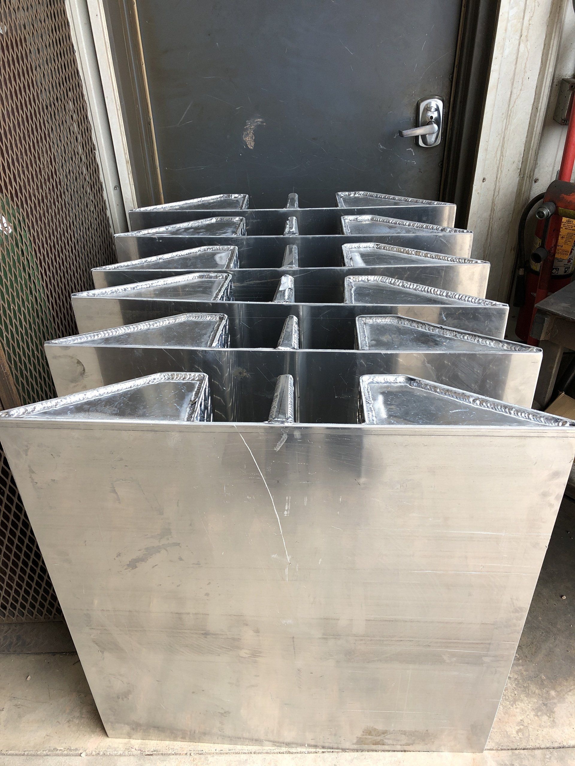 A bunch of aluminum planters are stacked on top of each other in front of a door.