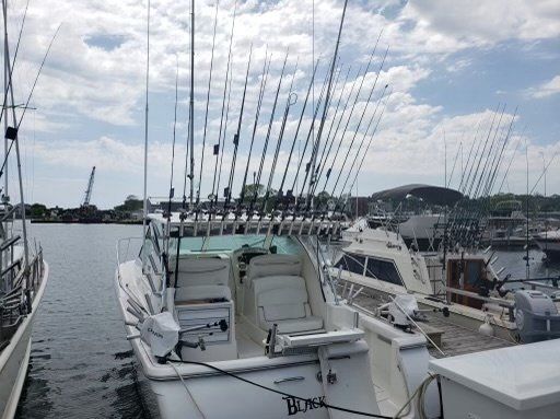 A boat with fishing rods attached to it is docked in a marina.