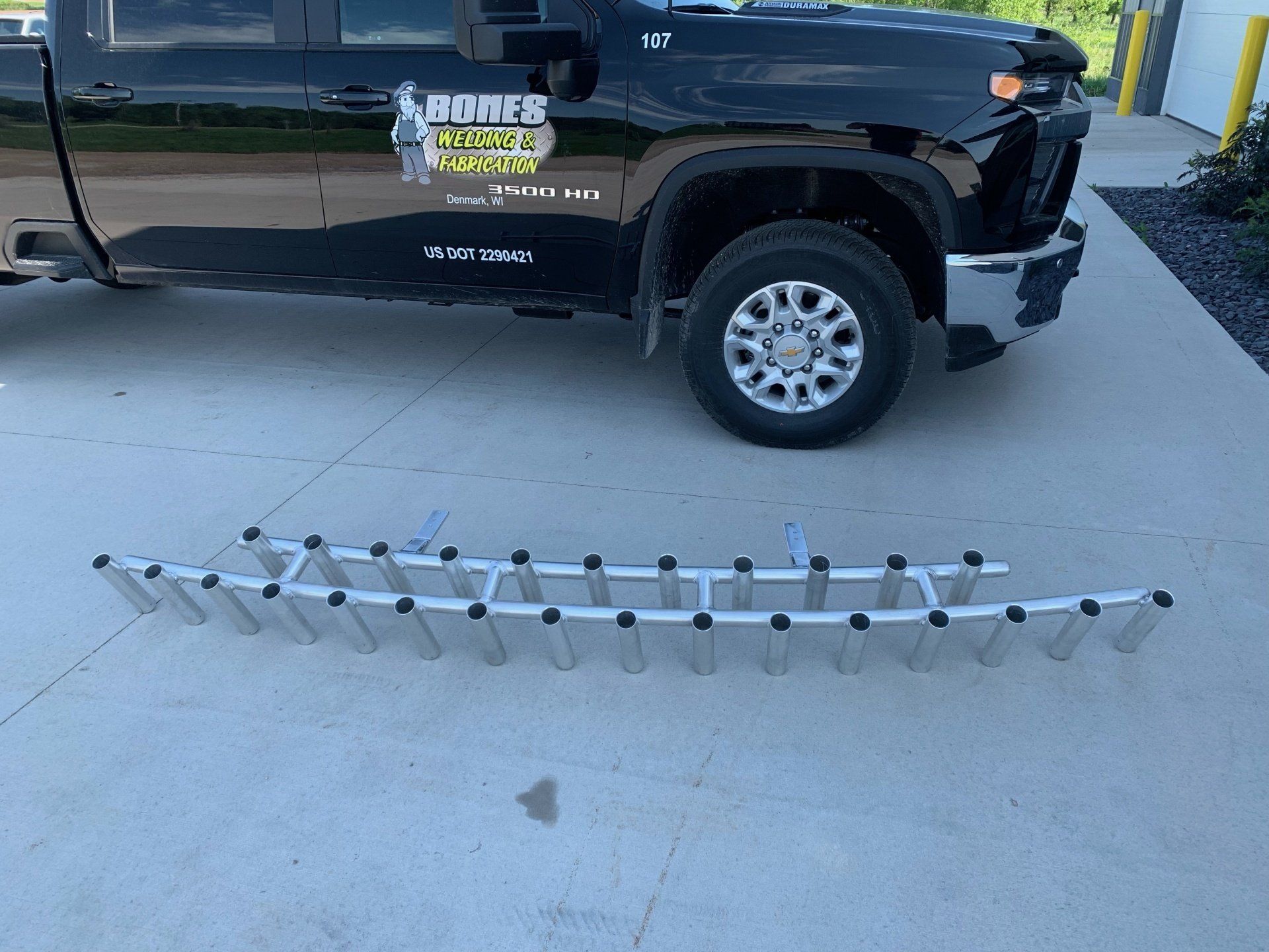 A black truck is parked in a parking lot next to a fishing rod rack.