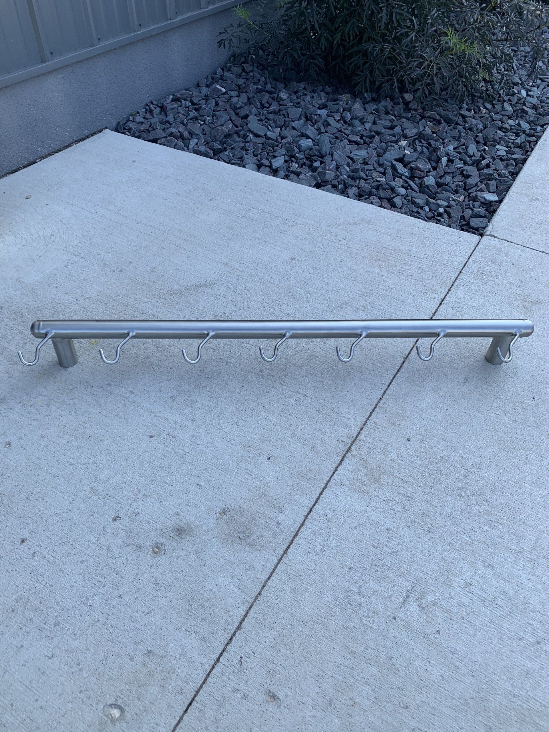 A metal railing is sitting on a concrete sidewalk next to a bush.