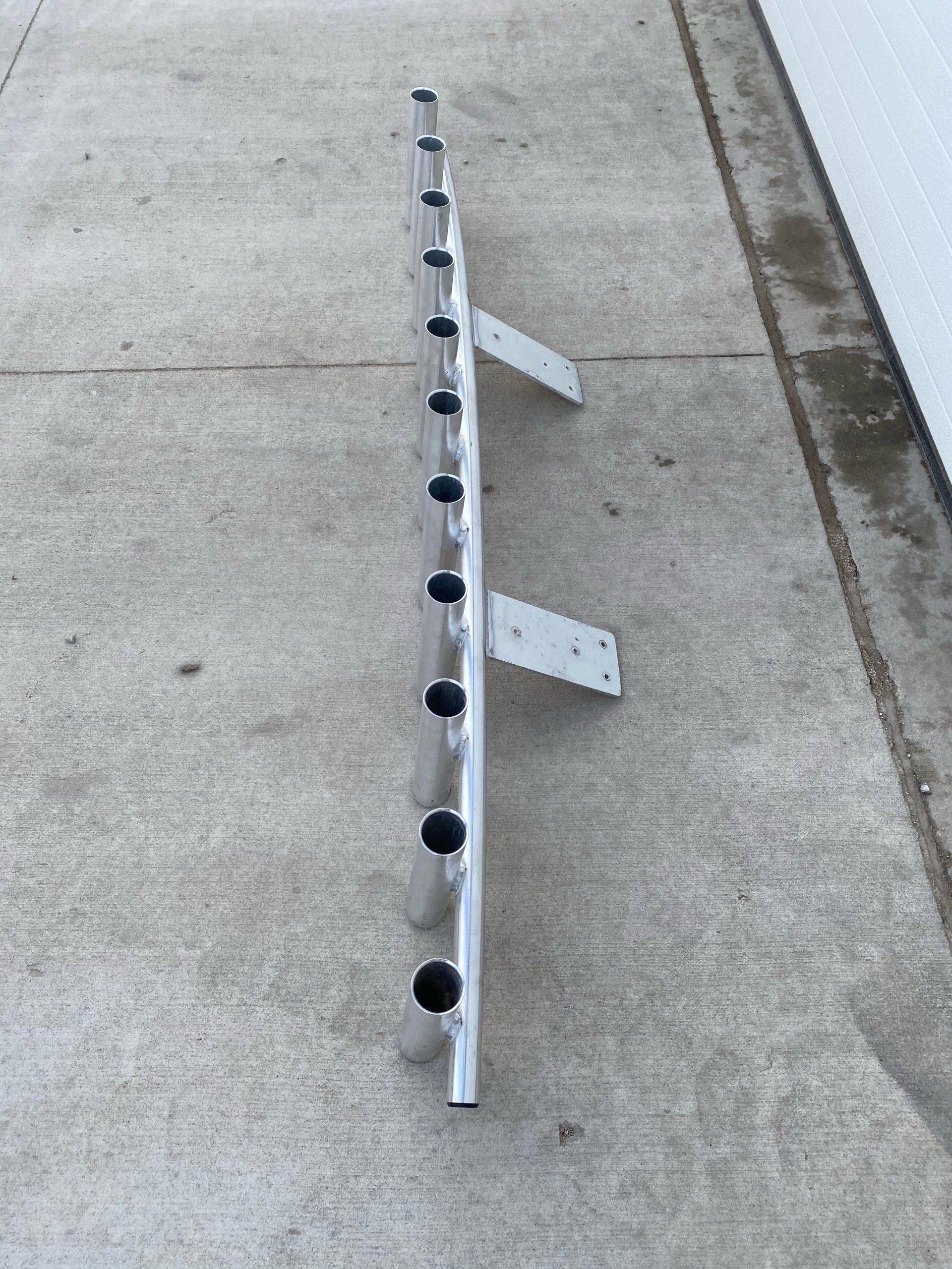 A metal railing with holes in it is sitting on a sidewalk next to a garage door.