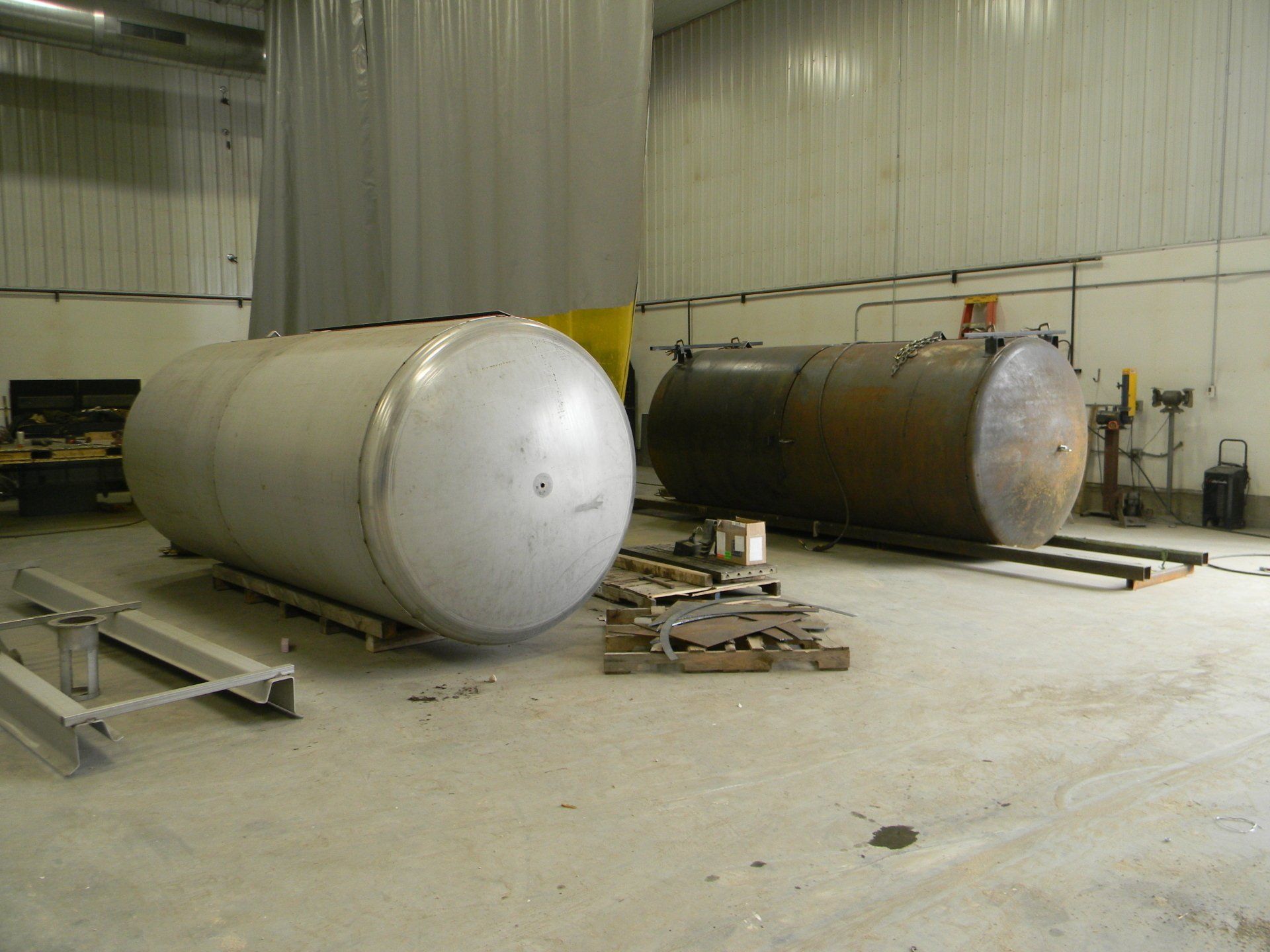 Two large metal tanks are sitting in a warehouse