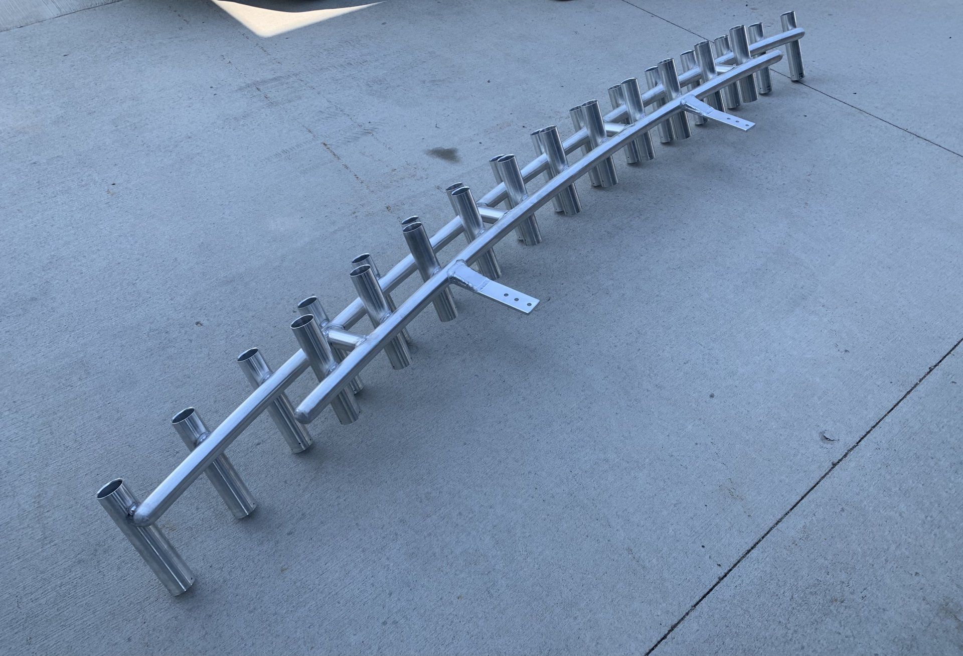 A row of fishing rods are sitting on a concrete surface.
