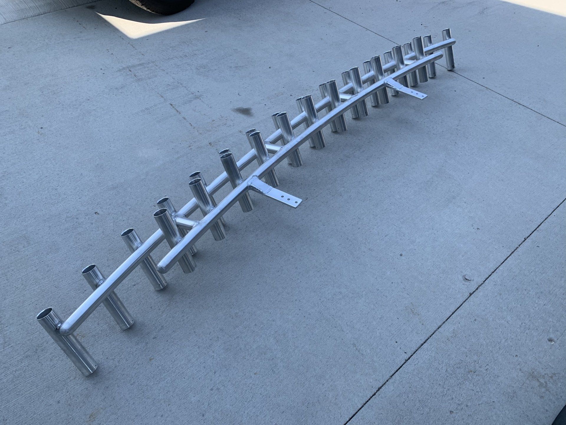 A row of fishing rods are sitting on a concrete surface.