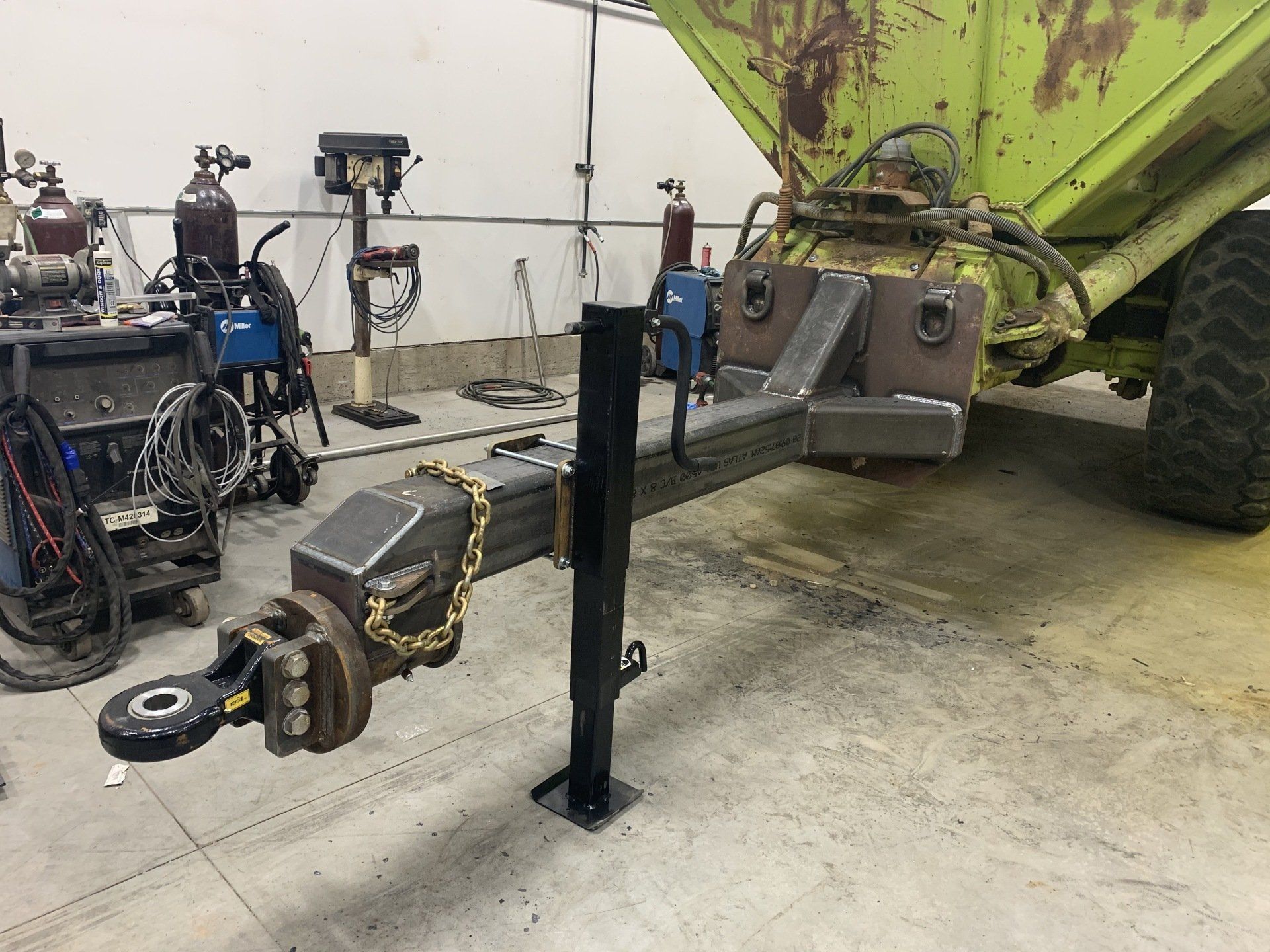 A trailer is sitting in a garage next to a tractor.