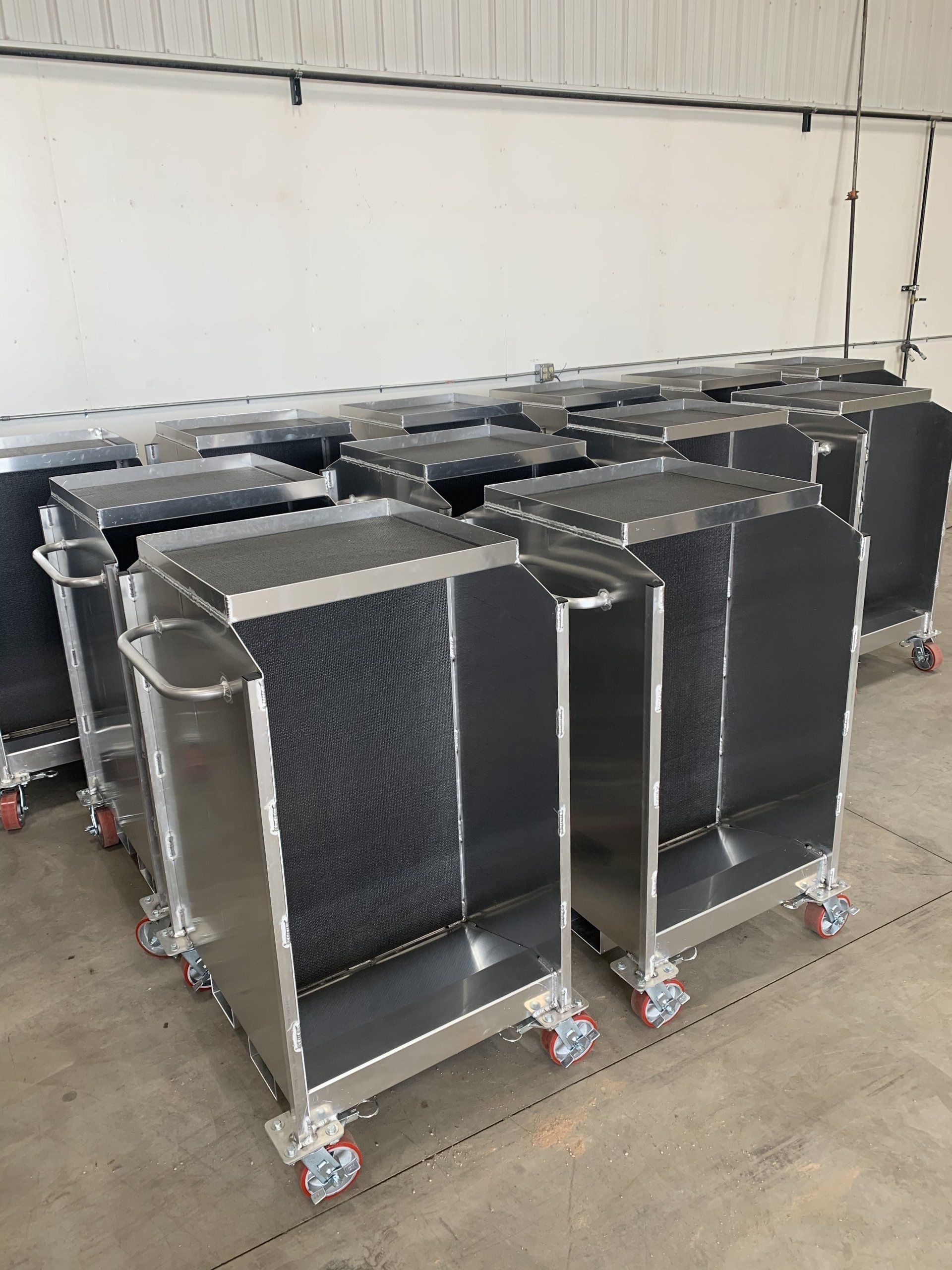 A row of stainless steel carts with wheels in a warehouse.