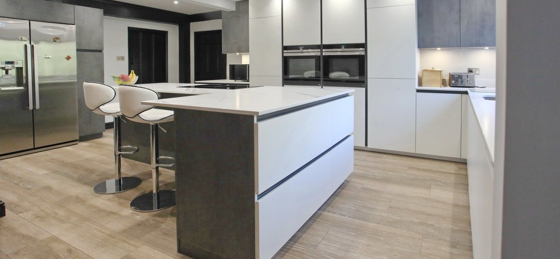 Kitchen island with seating area and a built-in wine fridge by exact by exact