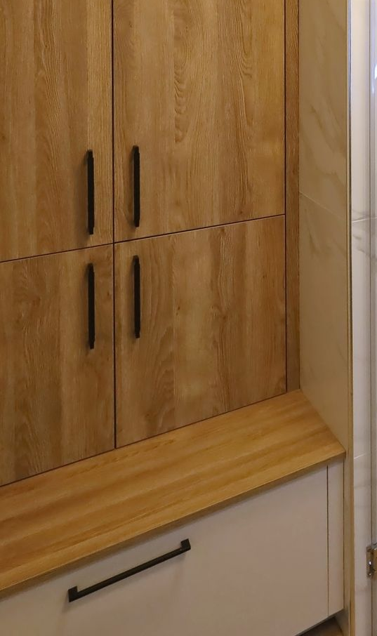 Wooden cabinet with black handles, a light-colored countertop, and a white cabinet below.