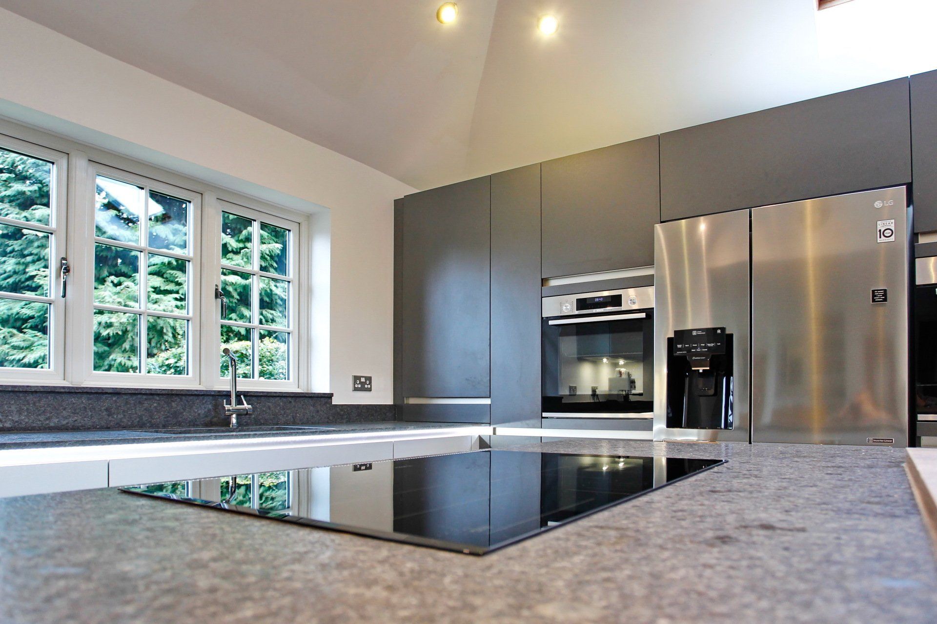 Harvey contemporary kitchen with grey, handleless units and teal furnishings. Designed by exact Kitchens in Wokingham.