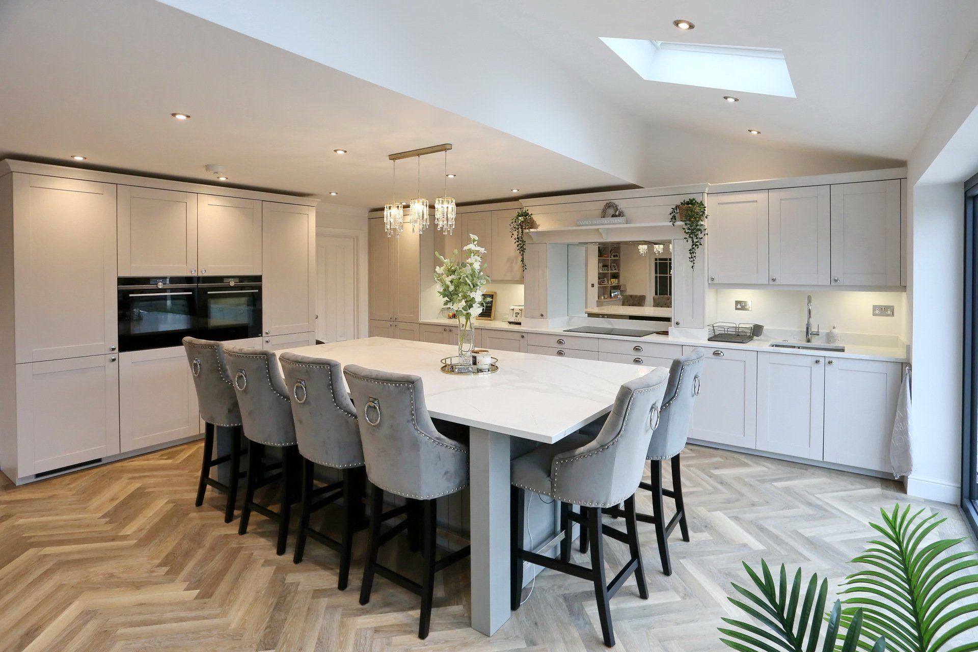 Modern shaker kitchen with island seating, grey cabinets, and white countertops.