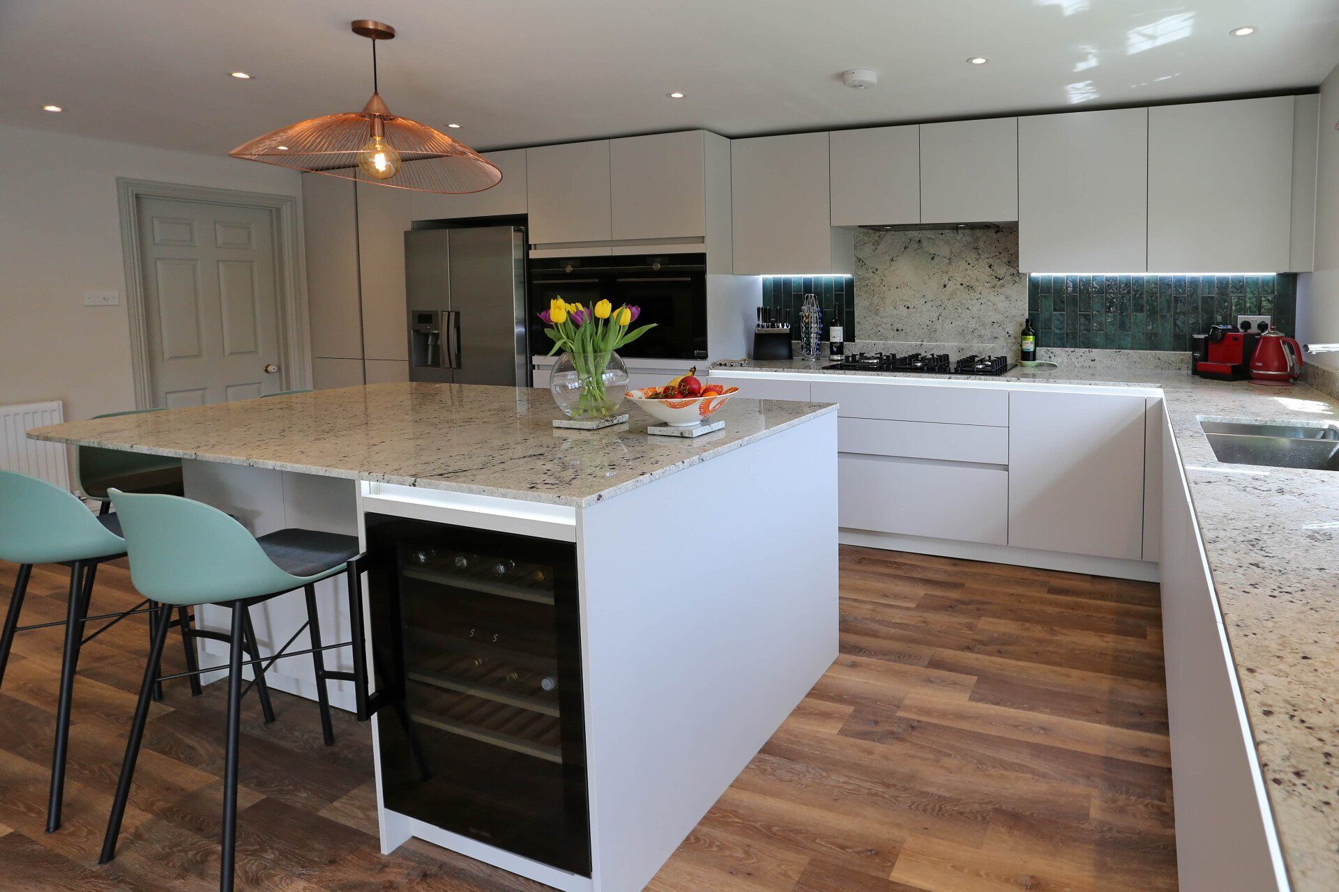 Harvey contemporary kitchen with grey, handleless units and teal furnishings. Designed by exact Kitchens in Wokingham.