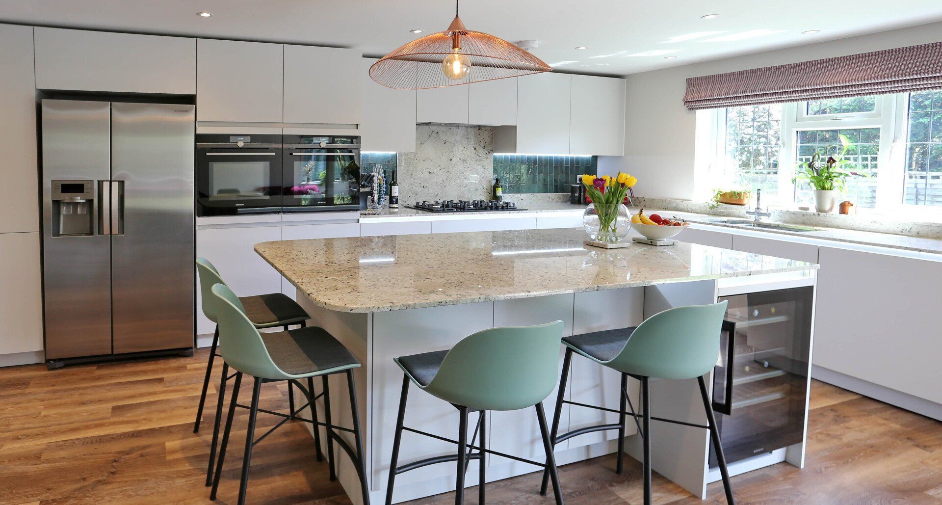 Kitchen island with seating area and a built-in wine fridge by exact by exact