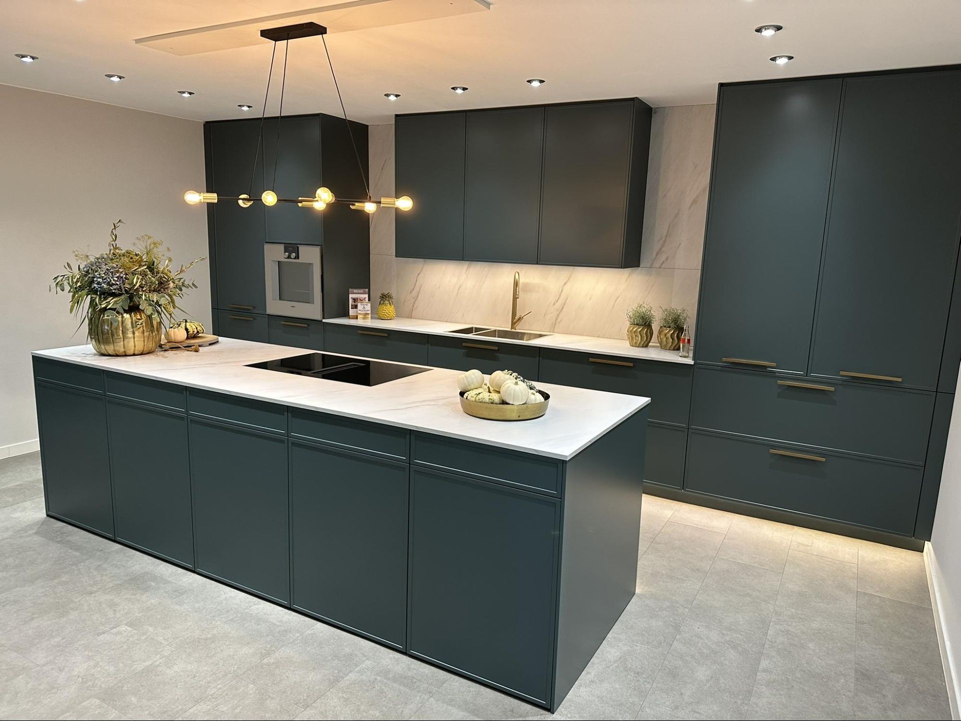 Slim framer shaker kitchen with deep green cabinetry and white worktops.