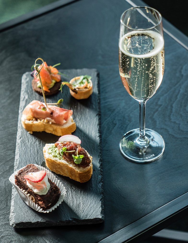 A tray of food and a glass of champagne on a table.